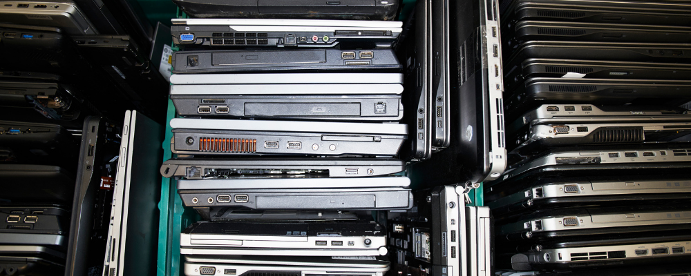Stacks of old laptops piled together for secure recycling and data protection.